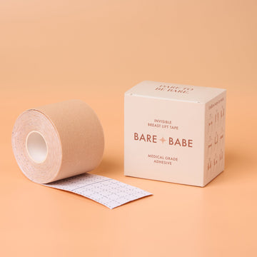 A roll of Bare Babe boob tape in Creme, partly unrolled to show its printed backing, beside its medical-grade adhesive box, breast lift tape for a backless wedding guest dress